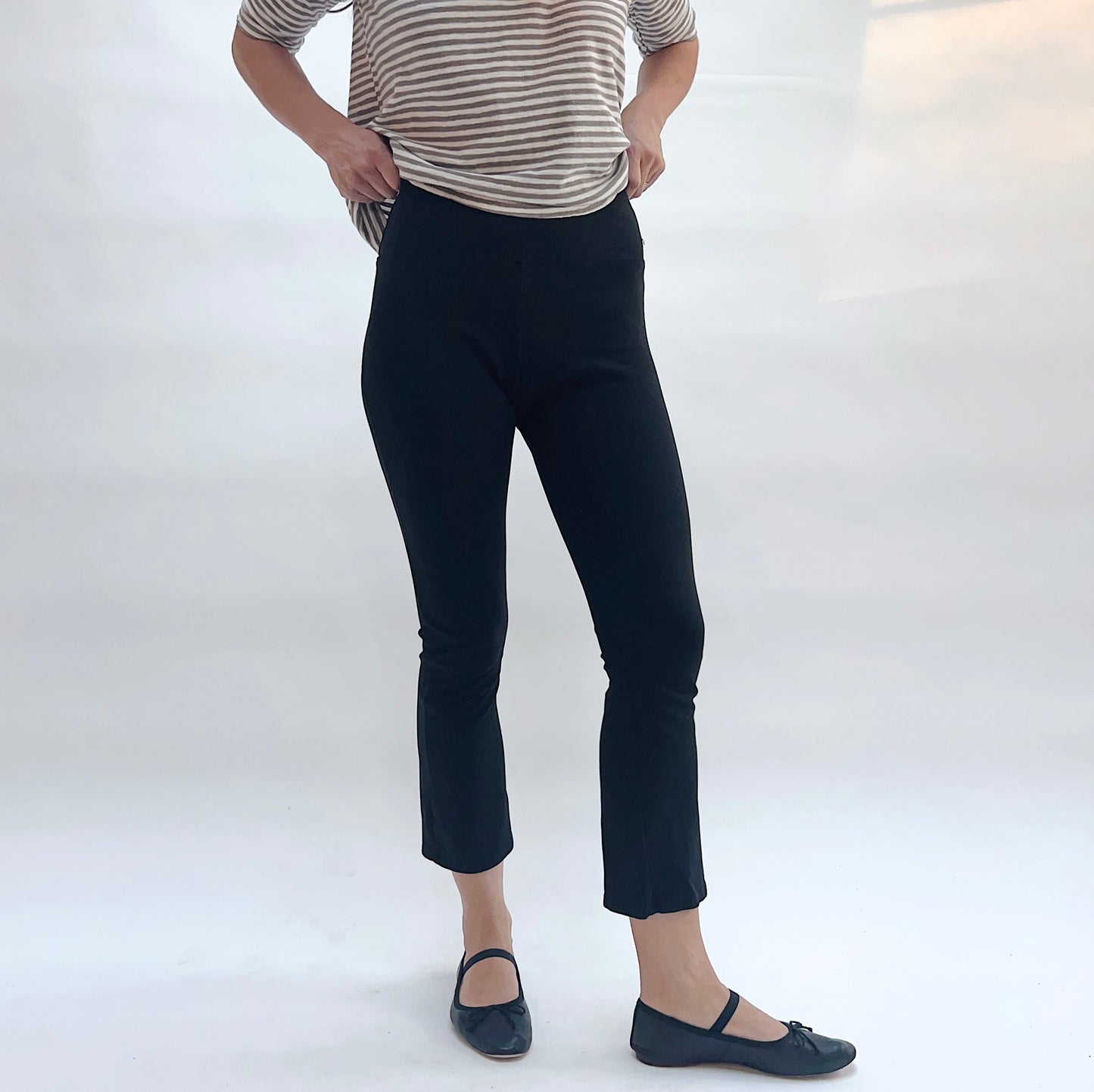 Person wearing black pants and a striped shirt on a white background
