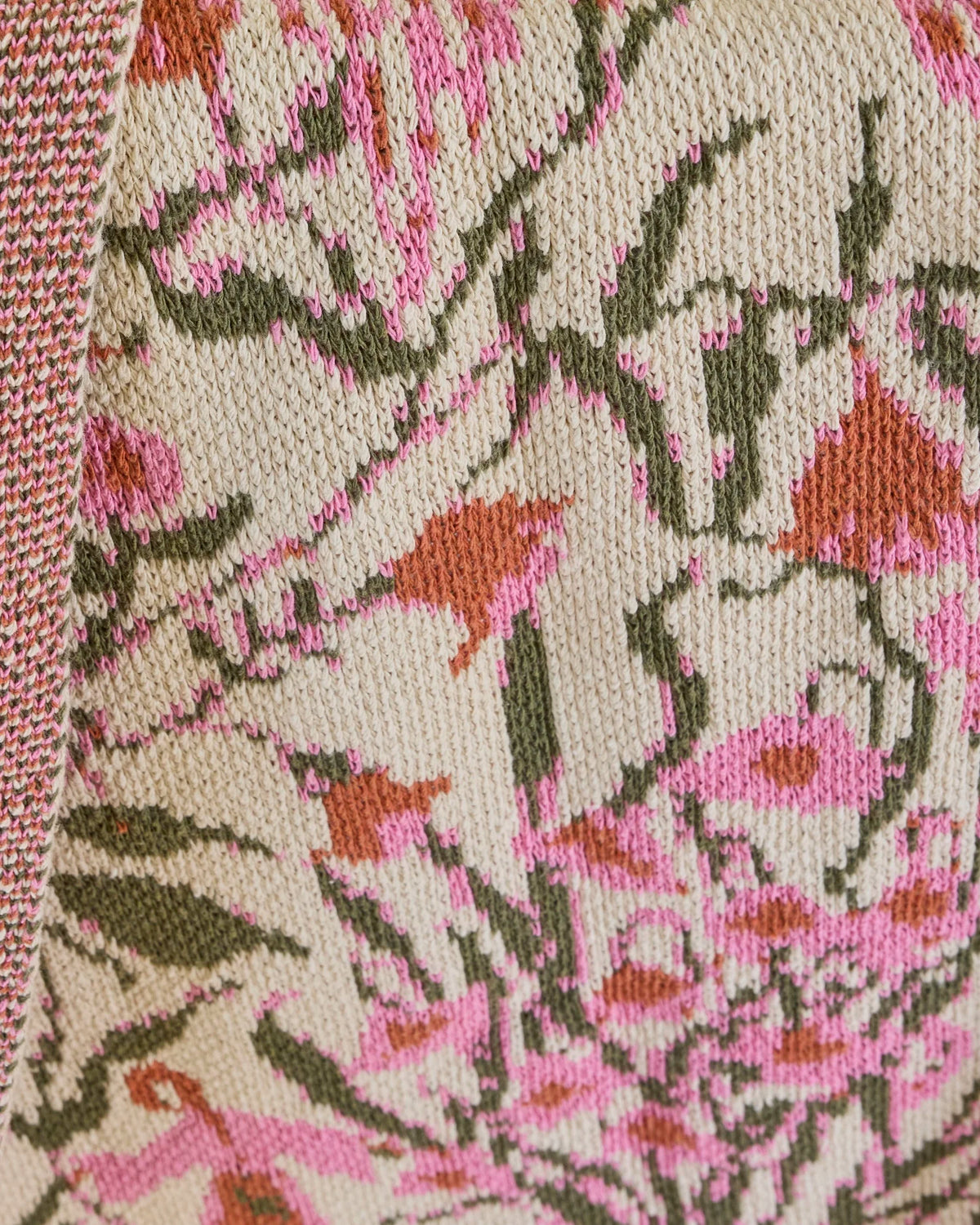 Close-up of the Spring Meadow Carnation blanket’s pink and rust flowers, green stems, and cream knit texture.
