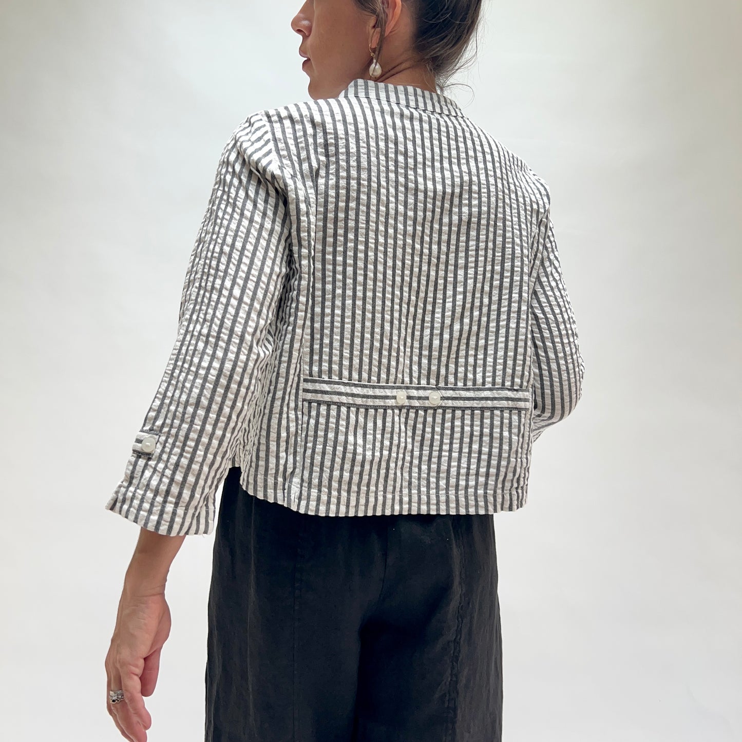 Person wearing a black and white checkered jacket on a plain background