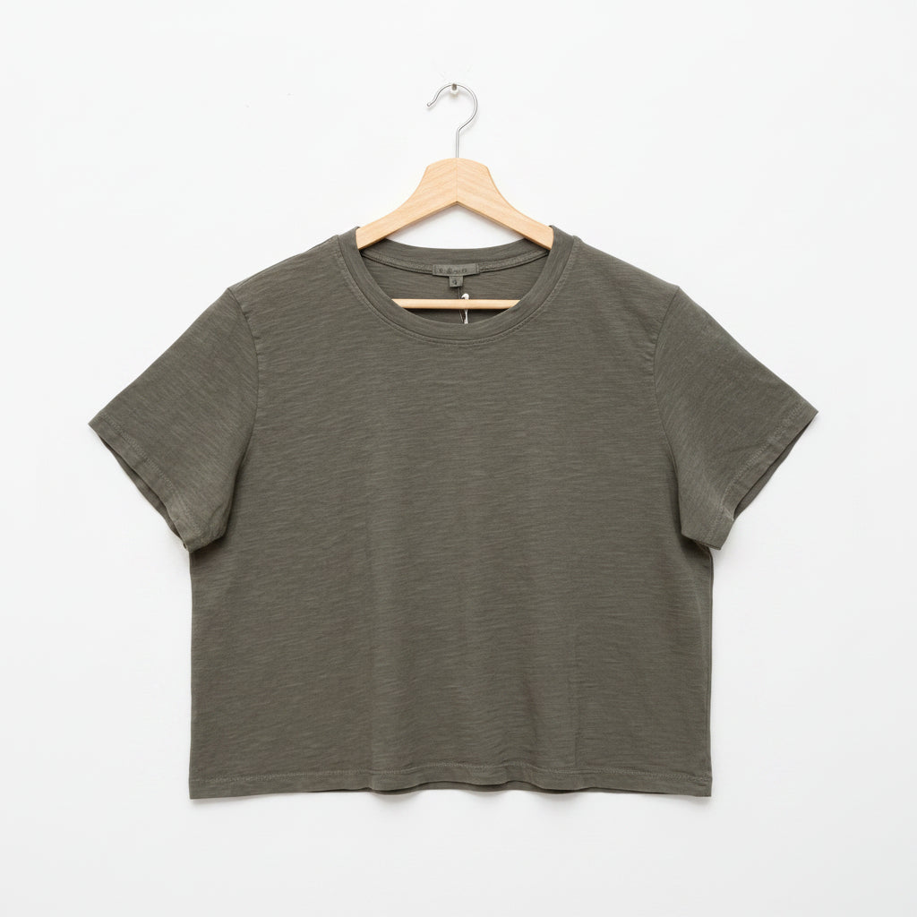 Gray t-shirt on a wooden hanger against a concrete wall.