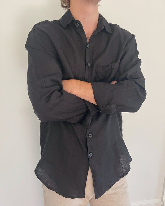 Model wearing Two Sons black linen button down shirt with arms crossed, styled with beige trousers