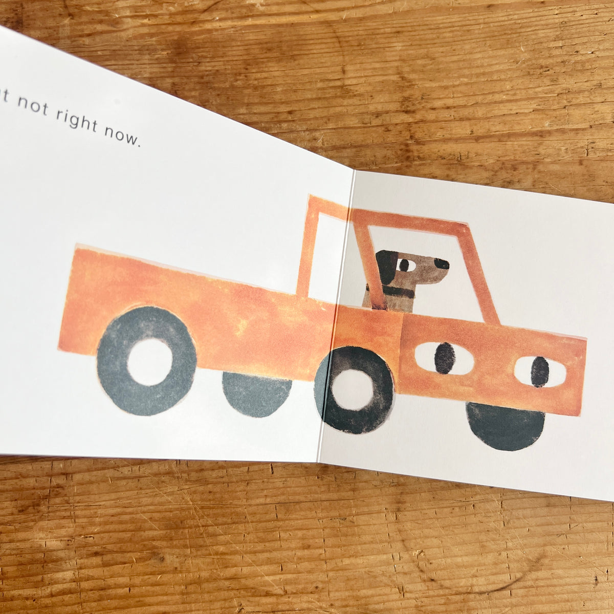 Open pages of Your Truck showing a dog sitting in the cab of an orange-red pickup truck with eyes.
