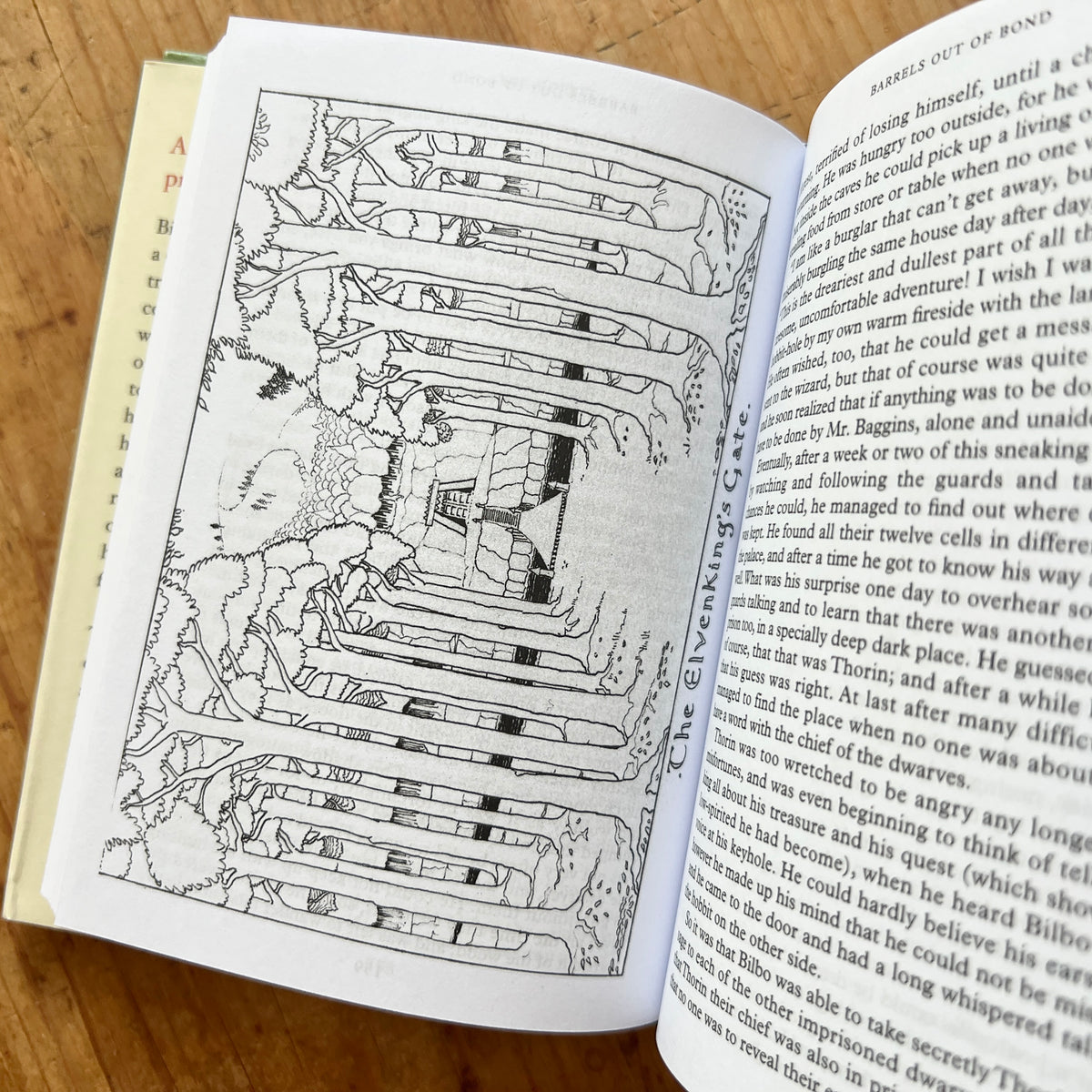 Open pages of The Hobbit: Pocket Edition showing a black-and-white illustration of the Elvenking’s Gate beside story text.
