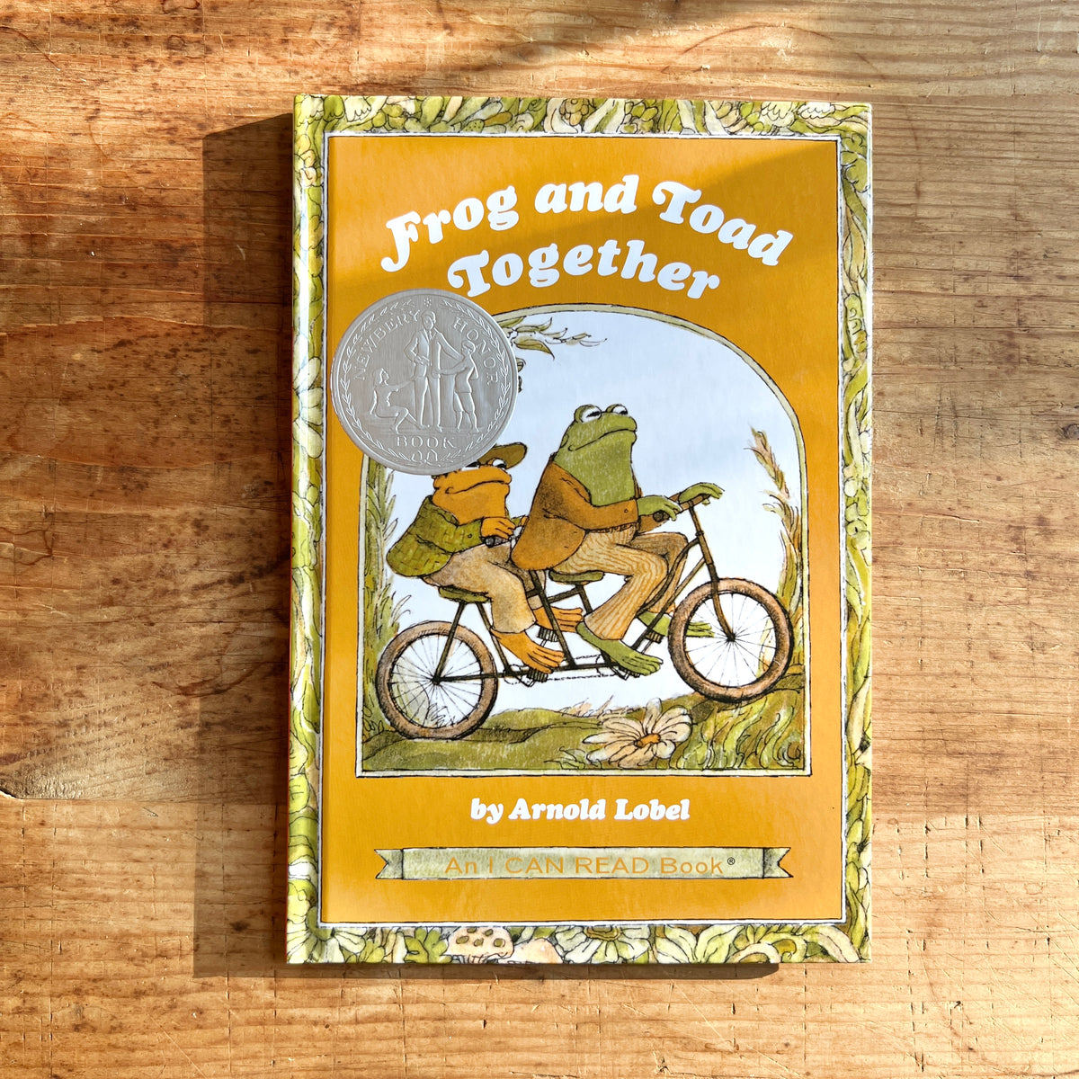 Hardcover of Frog and Toad Together by Arnold Lobel, showing the friends riding a tandem bicycle on the yellow cover.

