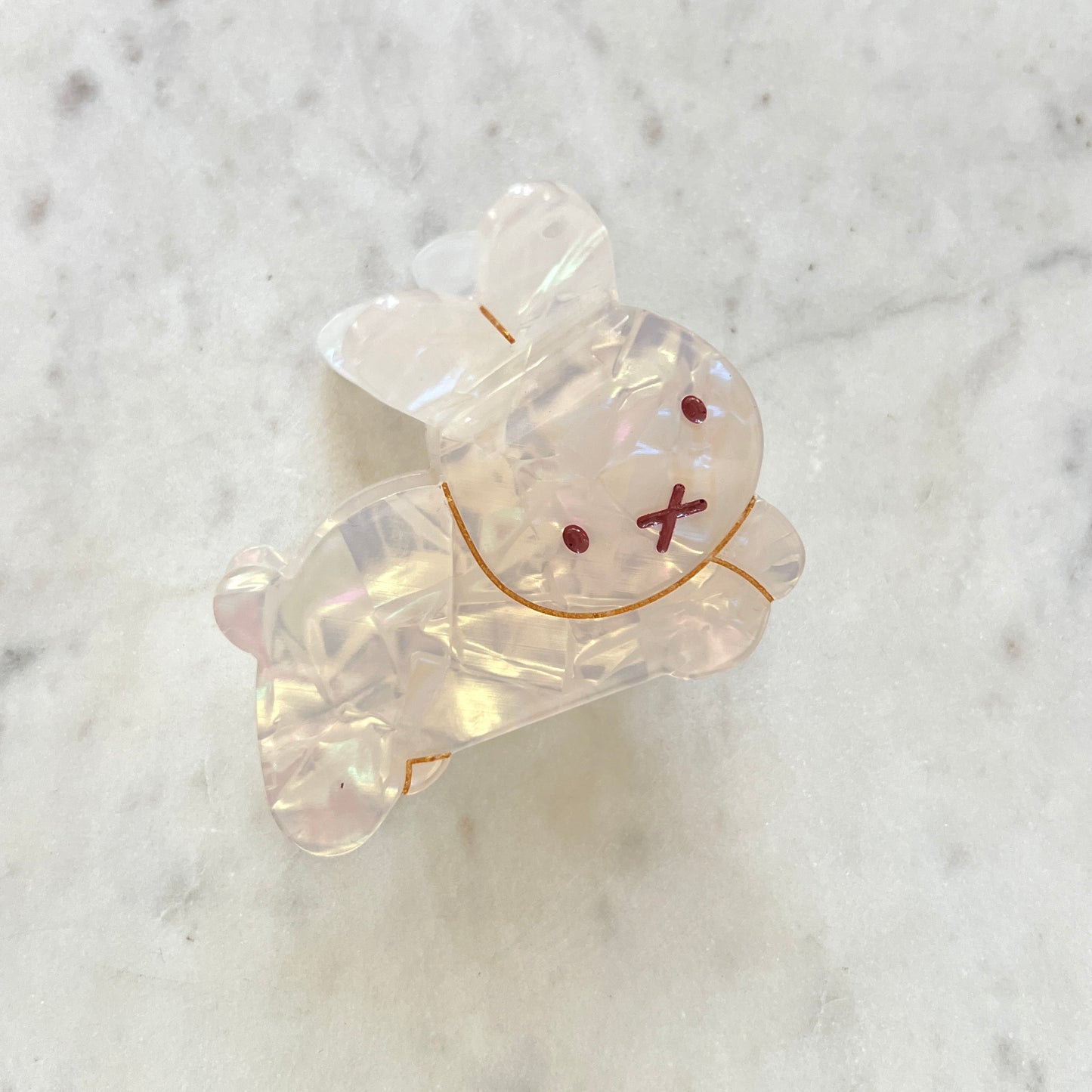 Clear resin bear-shaped object with red eyes and X-shaped mouth on a marble background