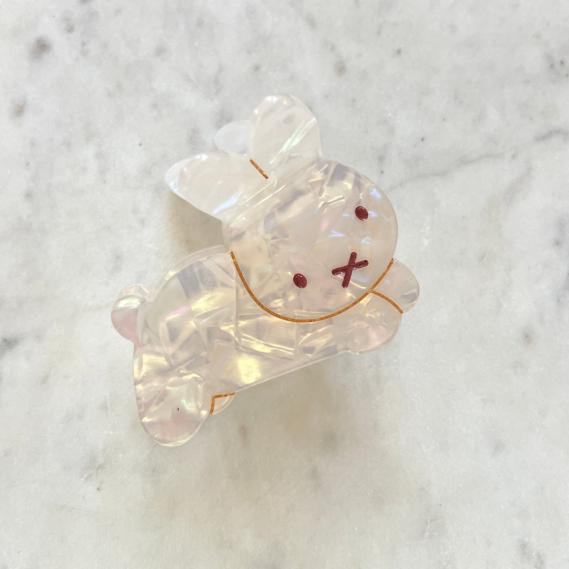 Clear resin bear-shaped object with red eyes and X-shaped mouth on a marble background