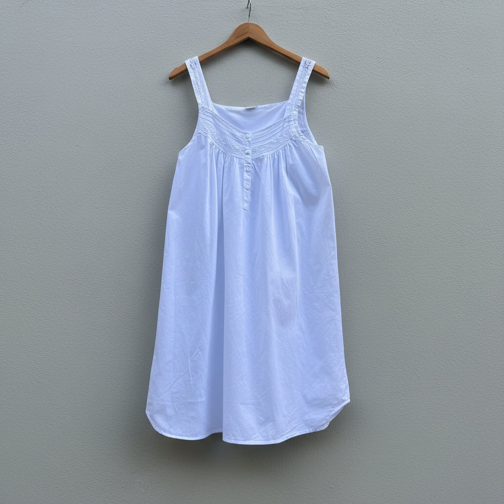 White dress on a wooden hanger against a gray wall