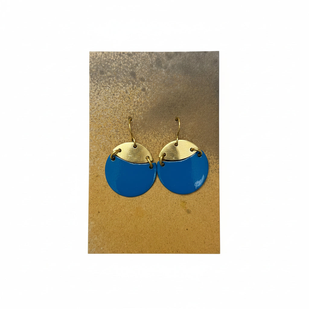Pair of blue and gold earrings on a beige card against a textured white background