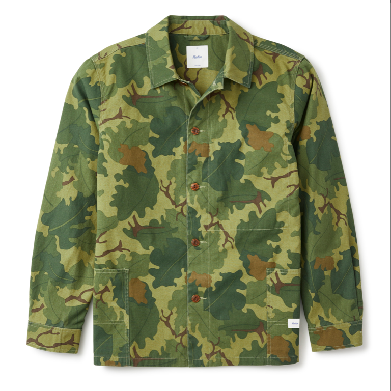 Katin Task Coast in Camo — flat lay front view of a relaxed cotton chore coat in woodland camo print with a spread collar, brown button front closure, two lower patch pockets, contrast stitching, and a woven label at the hem, on a white background