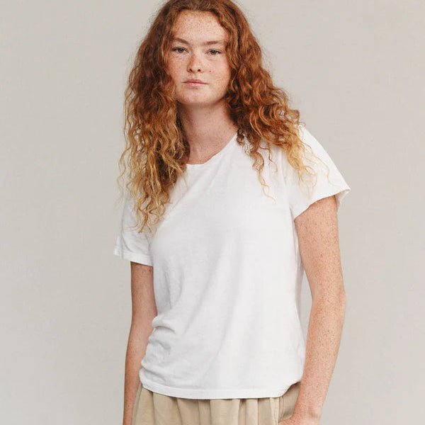 Person wearing a white t-shirt and beige pants against a plain background
