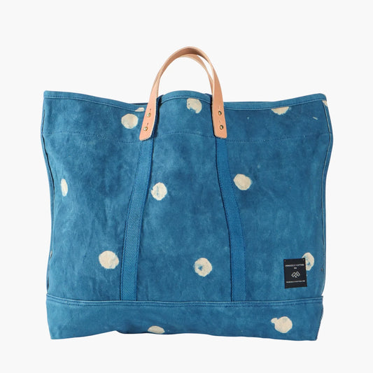 Blue tote bag with white floral patterns and brown handles on a white background