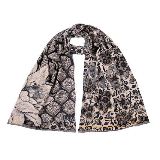 Létol Louise Scarf in Noir, looped and laid flat against a white background showing both sides simultaneously — one side featuring a bold black ogee lattice filled with Mughal tree-of-life motifs and a large botanical magnolia in the lower corner with the woven Létol signature, the other showing a dense all-over black floral and bird print on an off-white ground with sunflower, chrysanthemum, and fauna motifs, with a gold selvedge border visible at the hem
