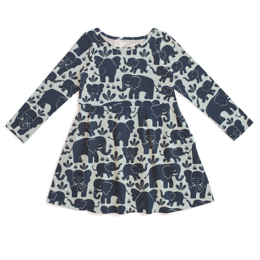 A long-sleeve baby dress with an all-over navy blue elephant print on a warm off-white background, laid flat against a white background.
