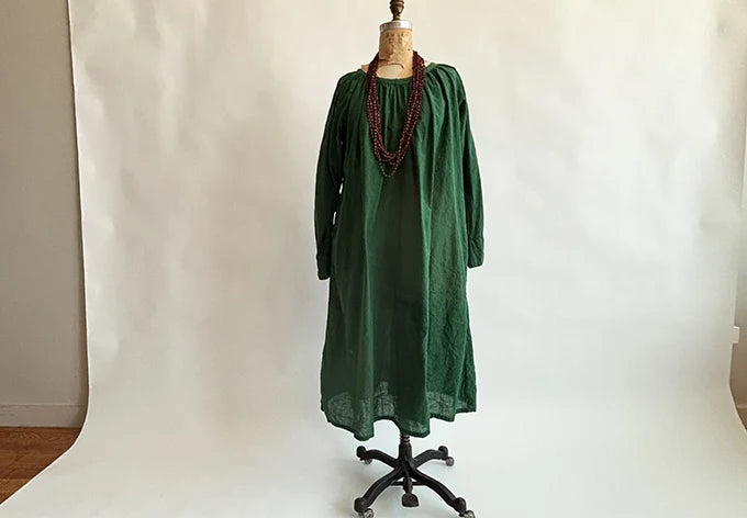 Front view of Auntie Oti Olive Gathered Dress on a dress form, showing the gathered neckline and long raglan sleeves.

