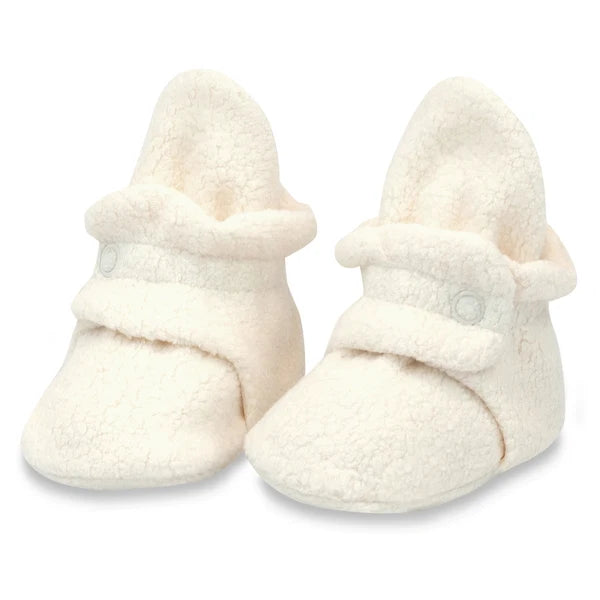 Pair of Zutano Cream fleece baby booties shown upright, with wraparound ankle straps and snap closures.
