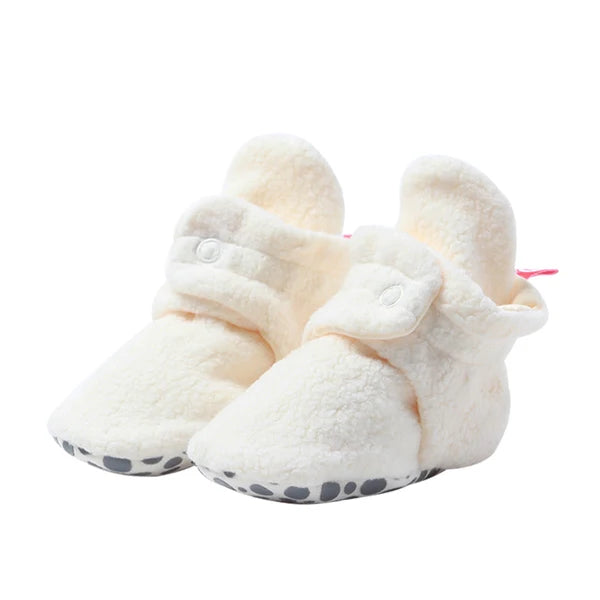 Front angled view of Cream fleece baby booties, with dotted gripper soles visible along the toe edges.
