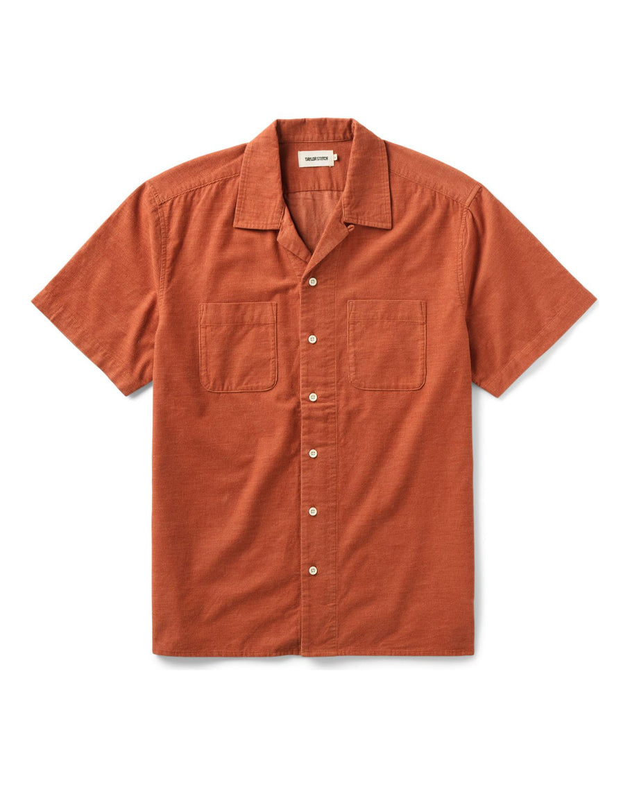 Model wearing Mollusk Surf Shop Cosmo Shirt in Saffron, front three-quarter view showing warm saffron yellow 100% cotton double gauze, open camp collar, 5-button front placket, left-chest patch pocket, and relaxed boxy fit, styled with blue denim shorts against a concrete wall
