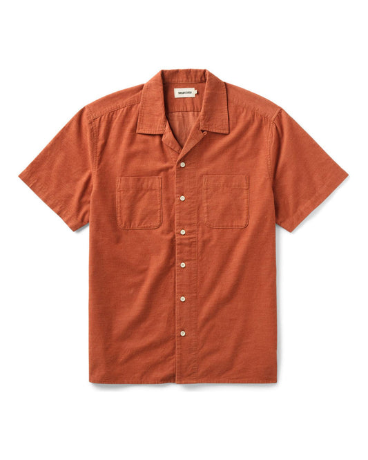Model wearing Mollusk Surf Shop Cosmo Shirt in Saffron, front three-quarter view showing warm saffron yellow 100% cotton double gauze, open camp collar, 5-button front placket, left-chest patch pocket, and relaxed boxy fit, styled with blue denim shorts against a concrete wall

