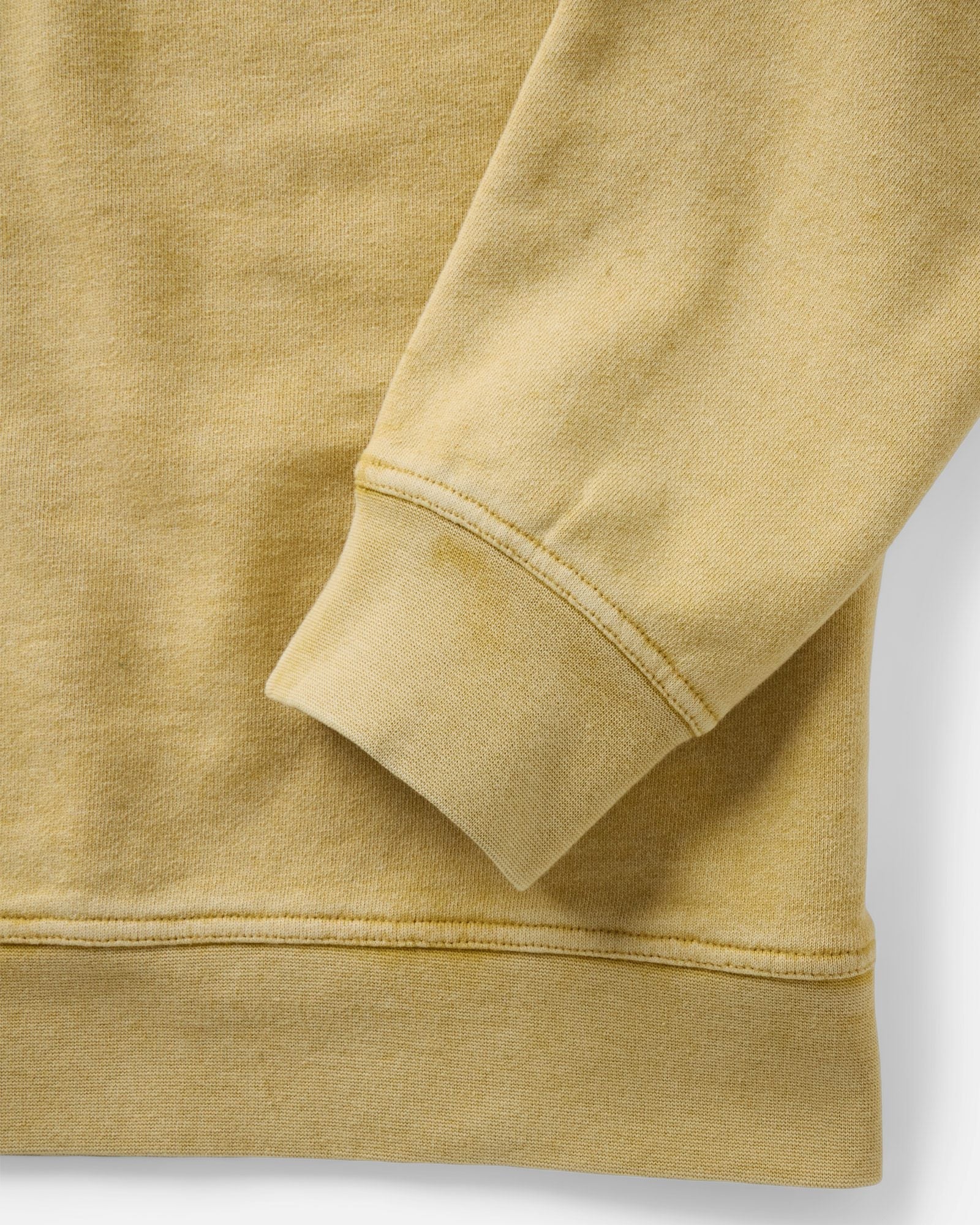 Close-up detail of the Taylor Stitch Sunset Henley sleeve cuff and hem, showing heavyweight ribbing and sun-faded goldfinch yellow French terry fabric