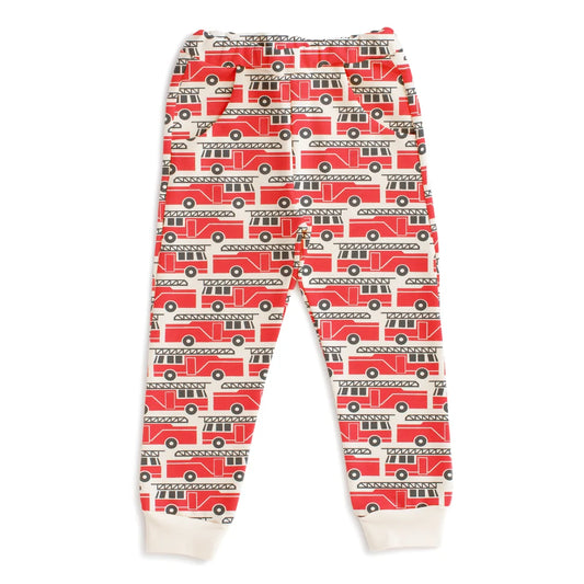 A pair of children's jogger pants featuring an all-over red fire truck pattern on a white background, with white ribbed cuffs at the ankles.