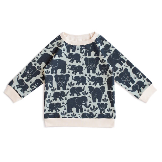 A long-sleeve baby sweatshirt featuring an all-over navy blue elephant pattern on a light sage green background, finished with solid cream ribbed cuffs, collar, and hem.