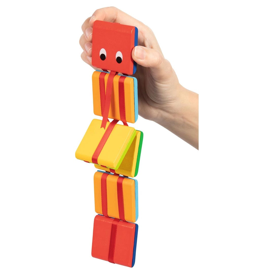 Hand holding the Goki Wooden Cascade Snake upright by its red snake head, demonstrating the cascading flip effect as the rainbow-colored wooden segments hang and flip downward in sequence
