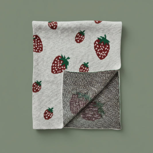 Folded blanket with strawberry pattern on a white background