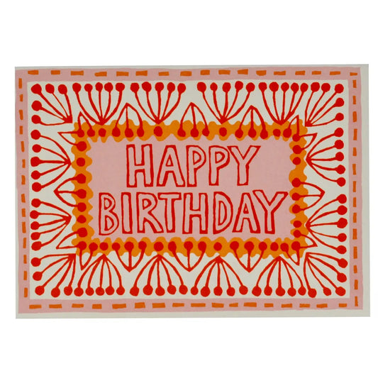 Happy Birthday written on a colorful pink and orange patterned card against a white background.
