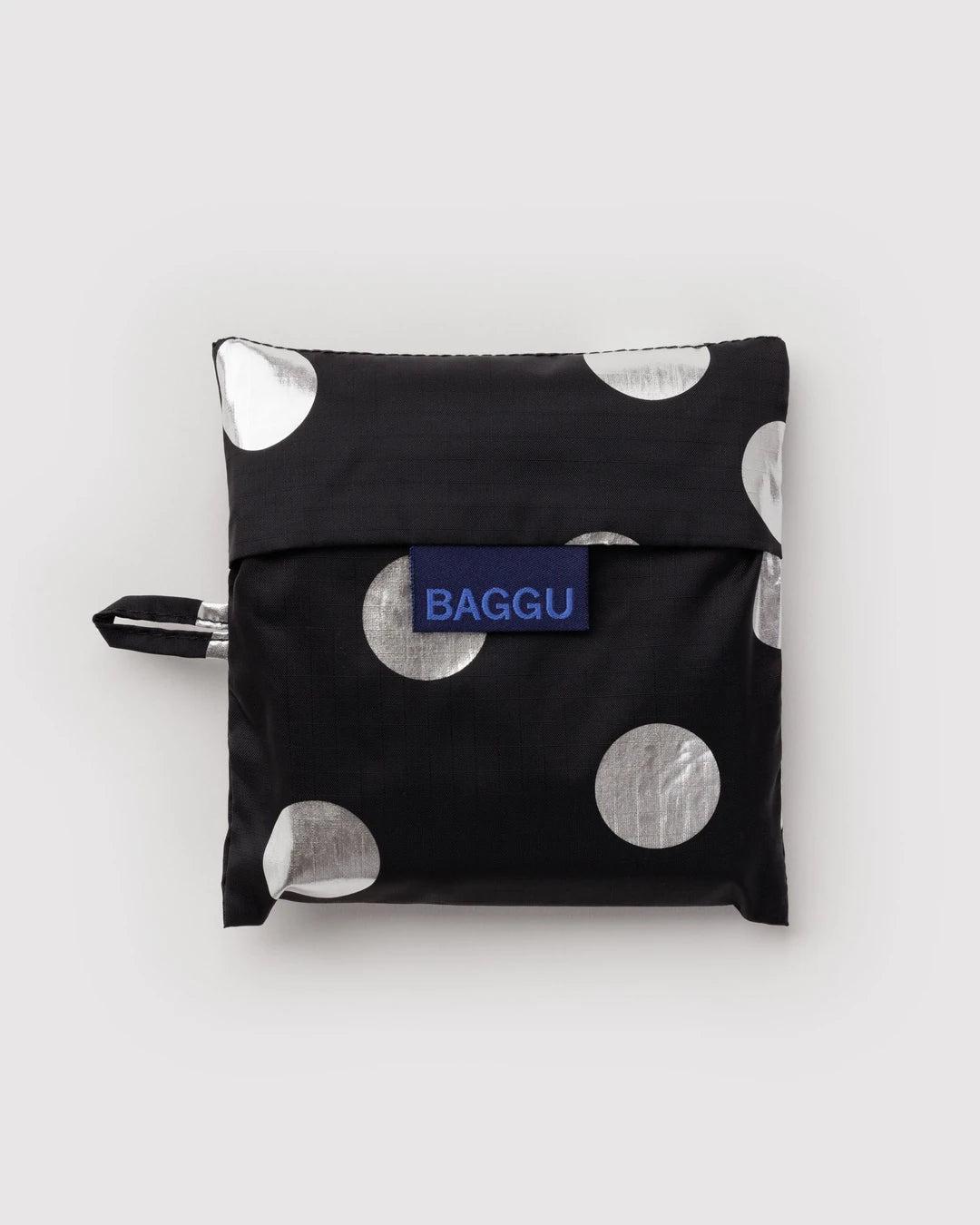 BAGGU Standard Baggu in Silver Metallic Polka Dot, folded into its matching black pouch with silver dots and a visible BAGGU label.
