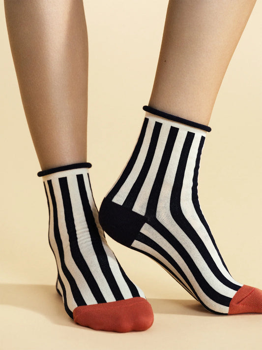 Black and white striped socks with red toes worn by a person on a beige background
