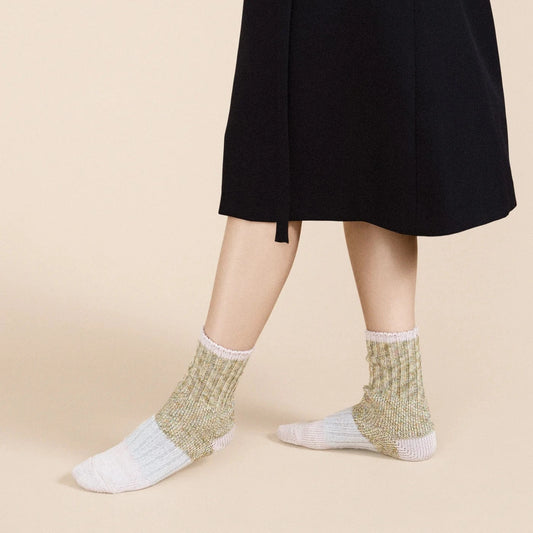 Pixie Dapple Crew socks in Pastel — sage and gold slub cotton crew with white heel and toe and pink rolled cuff, worn barefoot under a black midi skirt on a cream background
