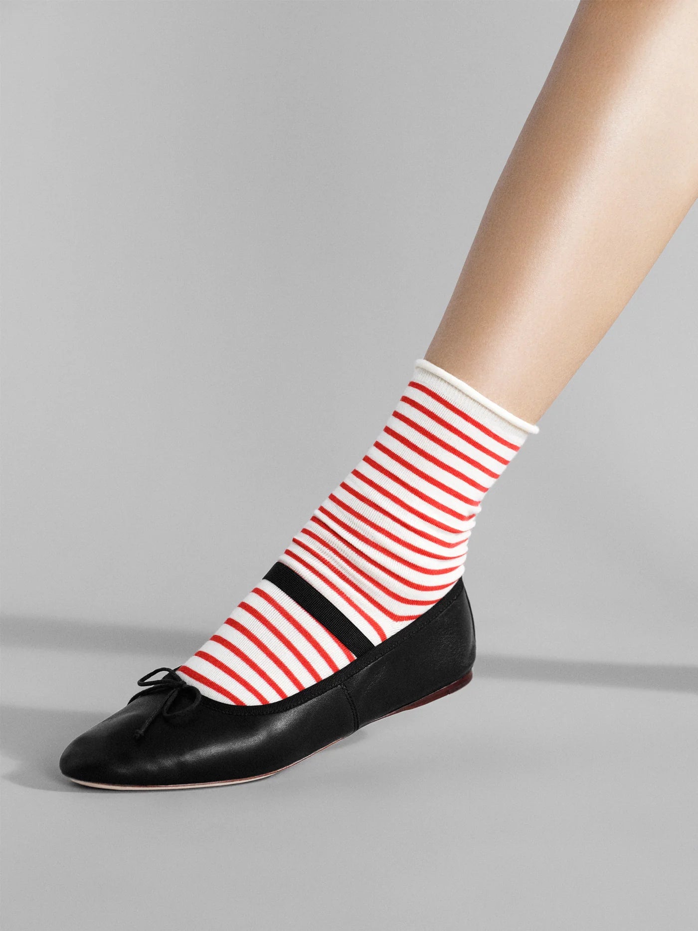 Nautical Stripe Crew socks in Pink — red and cream horizontal stripe crew with rolled cuff, worn with black bow ballet flats on a grey background
