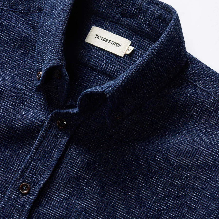 Close-up of the collar and button placket on The Jack in Indigo Waffle by Taylor Stitch, showing the deep indigo waffle-knit organic cotton texture and Taylor Stitch label