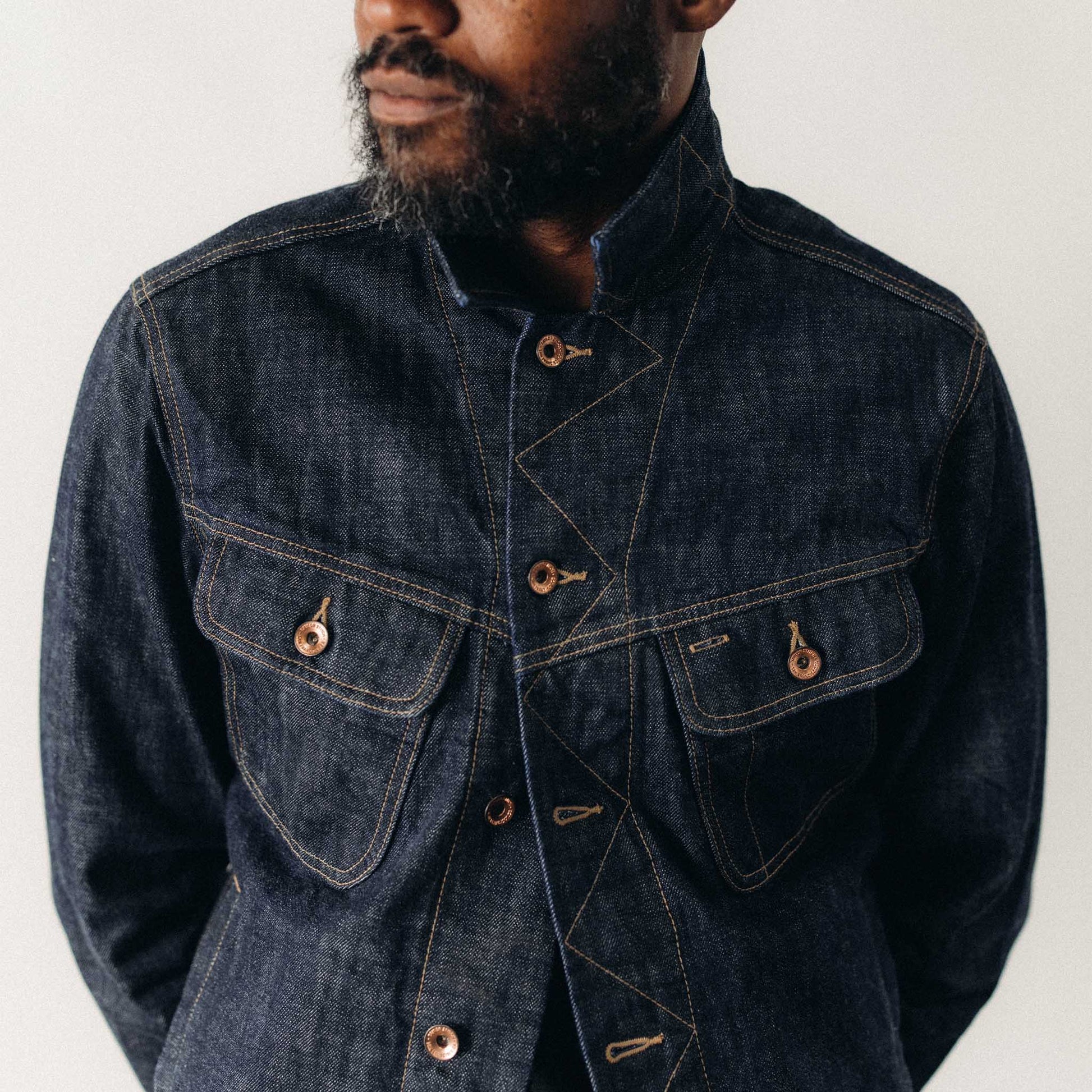 Close-up of a man wearing The Long Haul Jacket in Rinsed Organic Selvedge by Taylor Stitch, highlighting the chest pocket detail, copper hardware, and contrast stitching on the dark indigo denim.
