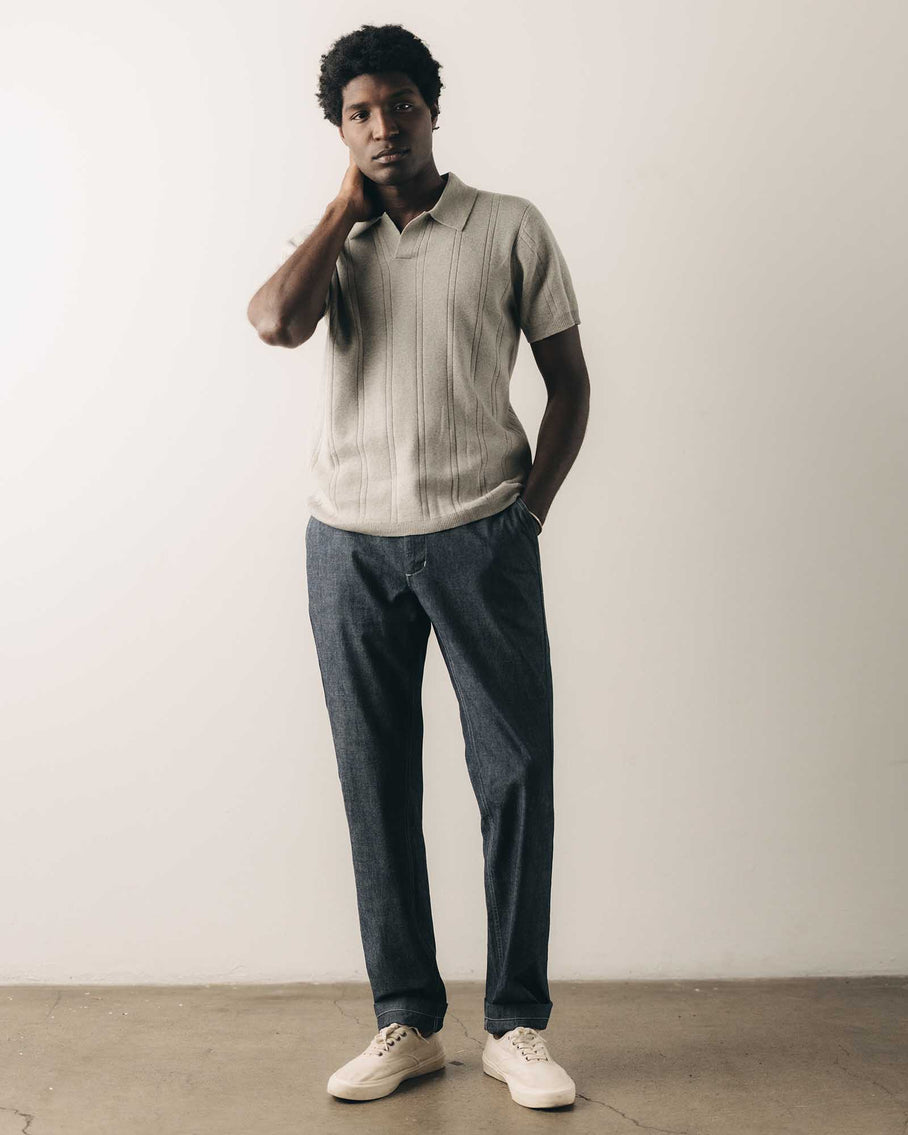 Man wearing a light-colored polo shirt and dark jeans against a plain background