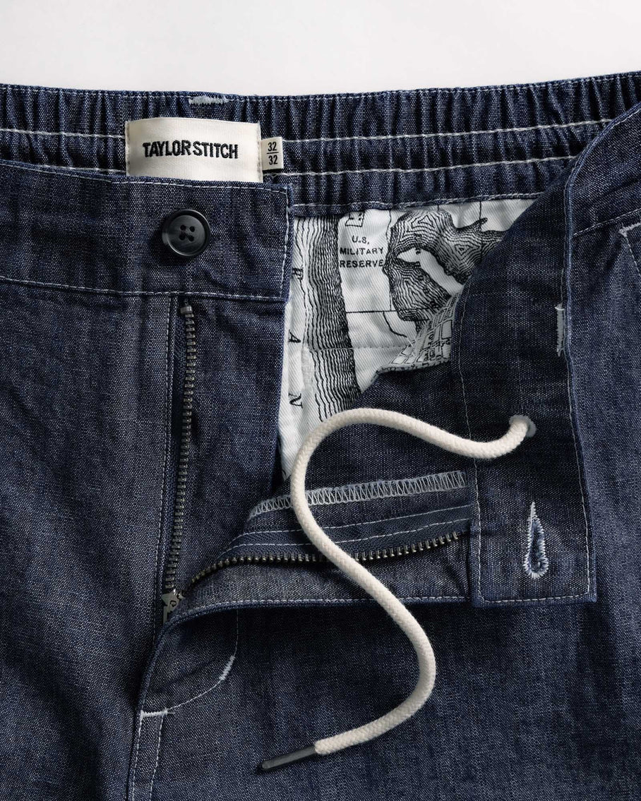 Close-up of dark blue denim shorts with a stethoscope and 'Taylor Stitch' label.