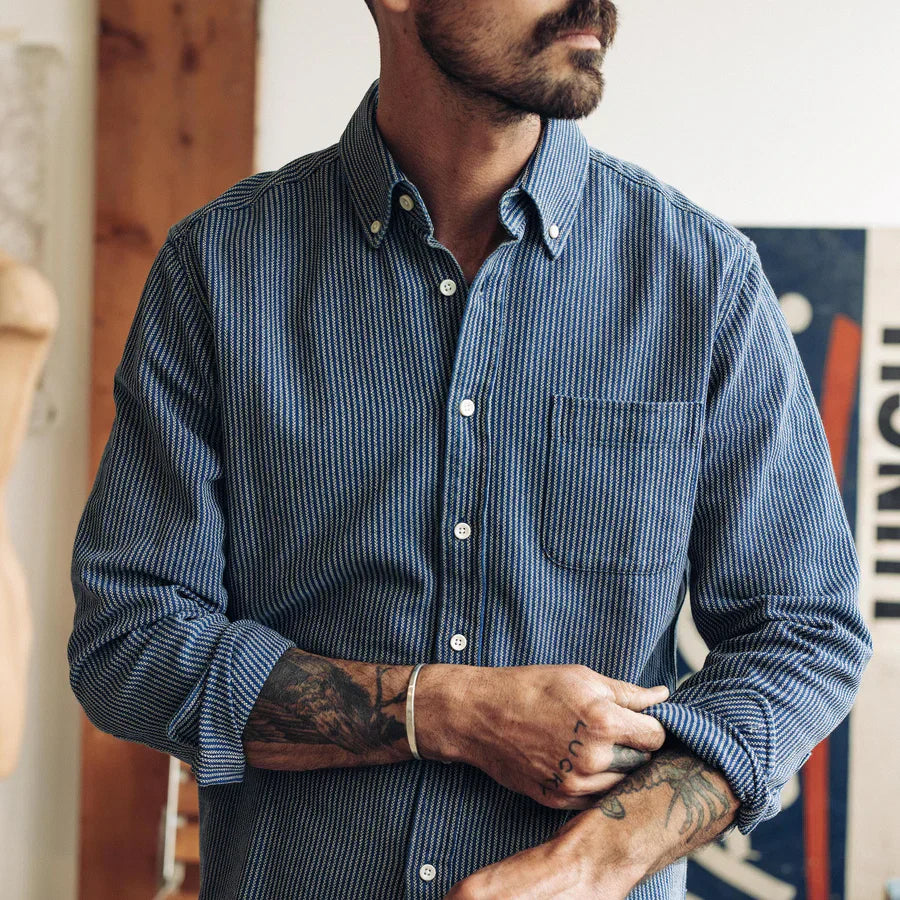 Man wearing The Jack in Roped Indigo by Taylor Stitch, showing the roped indigo texture and chest pocket detail with sleeves rolled to the forearm