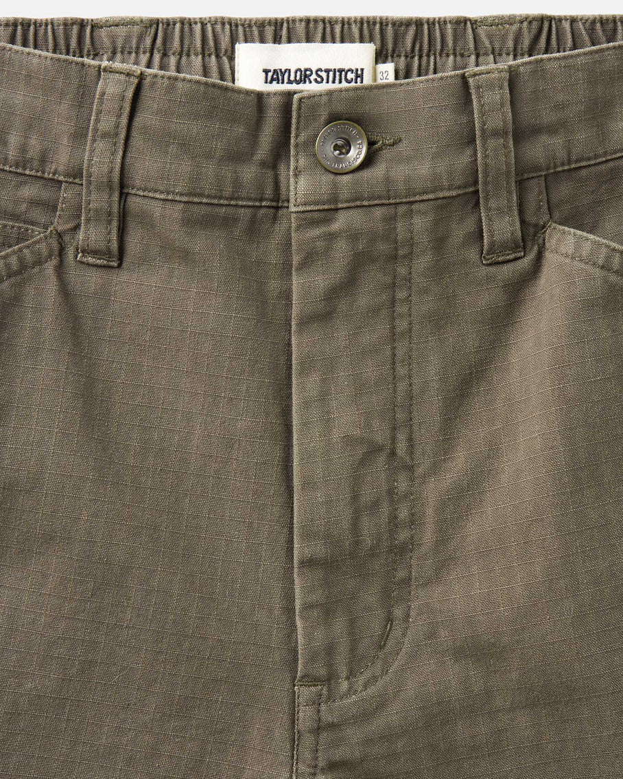 Close-up of a brown pants pocket with a button and Taylor Stitch label.