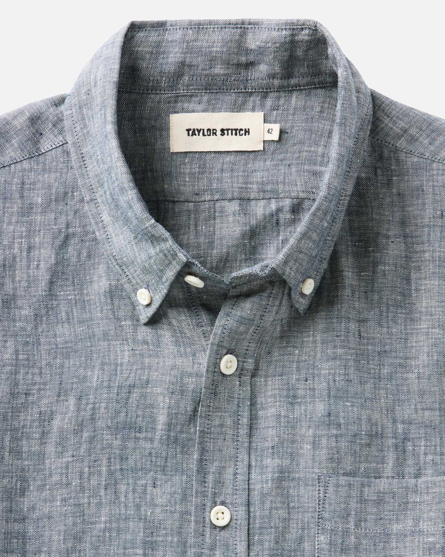 Close-up of Taylor Stitch The Jack in Ocean Linen collar and placket showing button-down collar with lock-stitched buttons, Taylor Stitch label, and ocean blue-grey washed European linen texture

