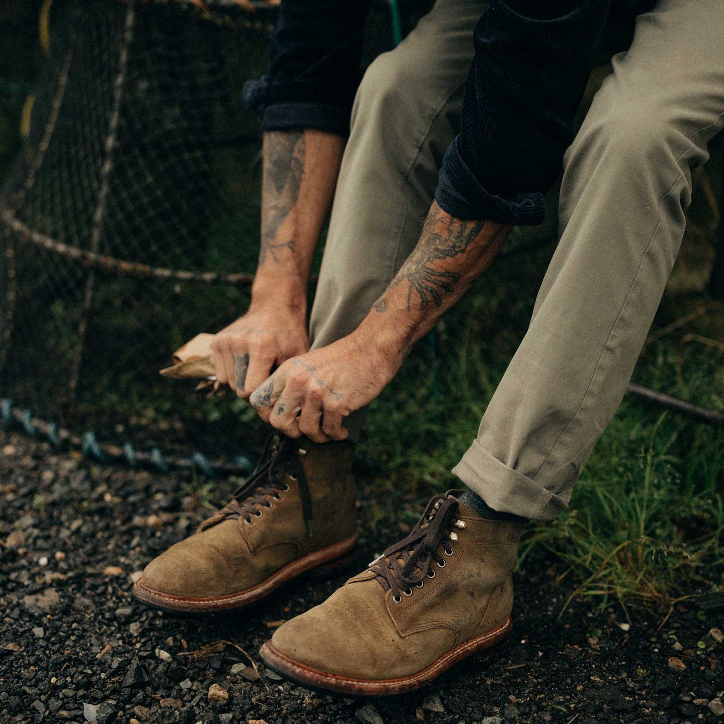 Person tying brown boots outdoors with a natural background