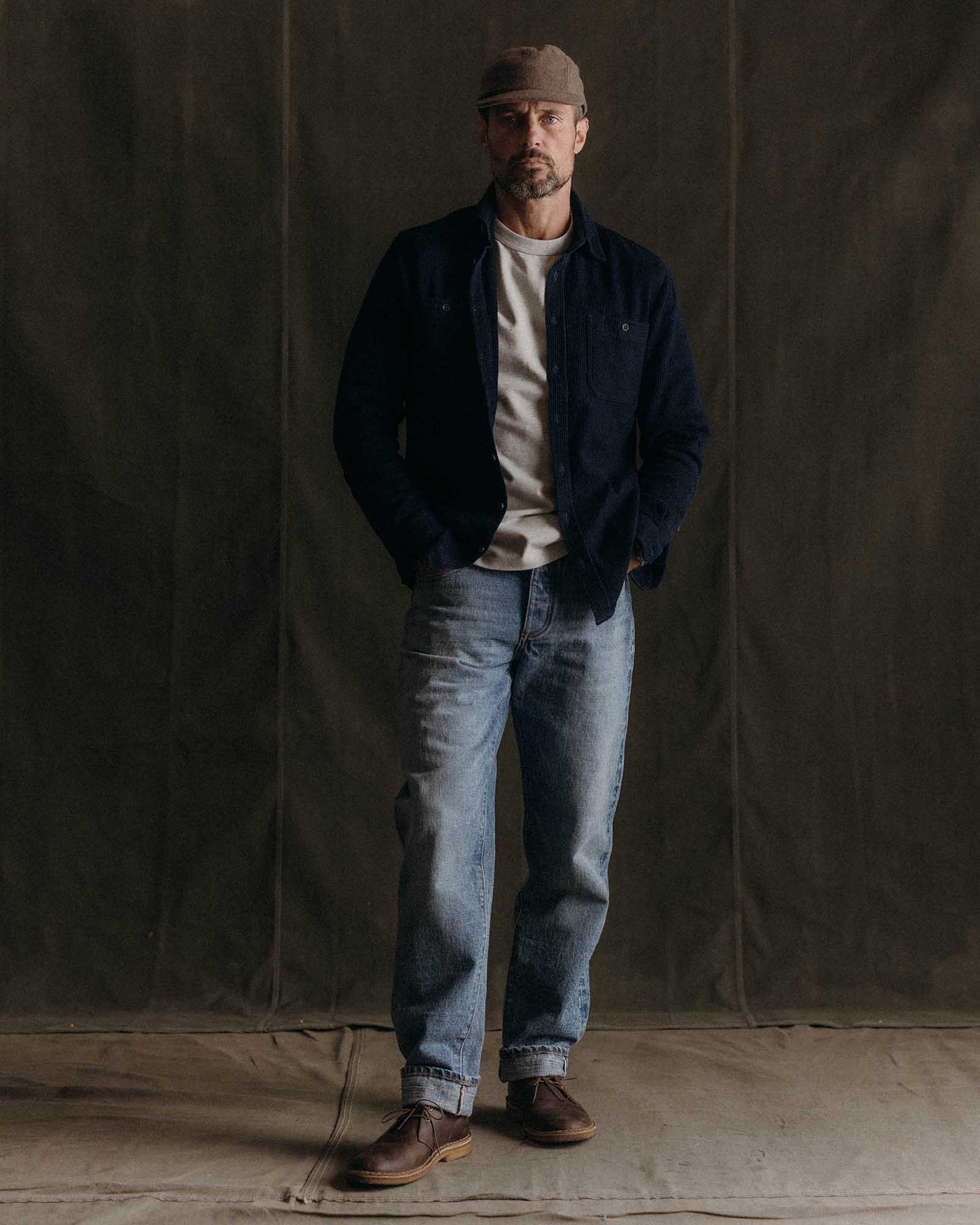 Close-up of Taylor Stitch Utility Shirt in Rinsed Indigo Sashiko showing pronounced horizontal sashiko weave texture, spread collar, and dark corozo-style buttons on deep rinsed indigo organic cotton
