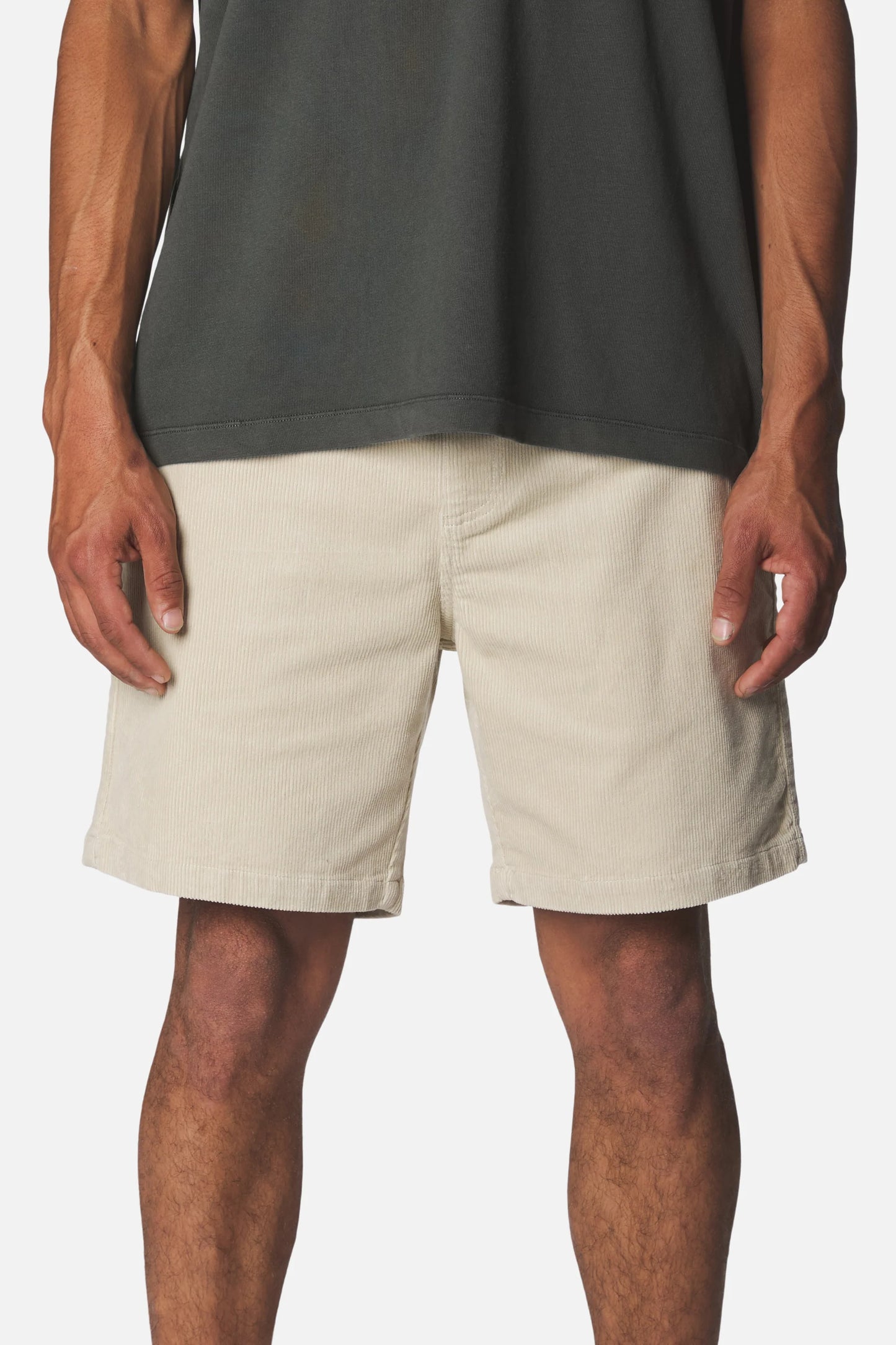 Katin Kord Patio Shorts in Pelican — front on-model view showing the elastic drawcord waistband, faux fly, and relaxed fit in pelican cream stretch corduroy, worn with a dark grey t-shirt on a white background