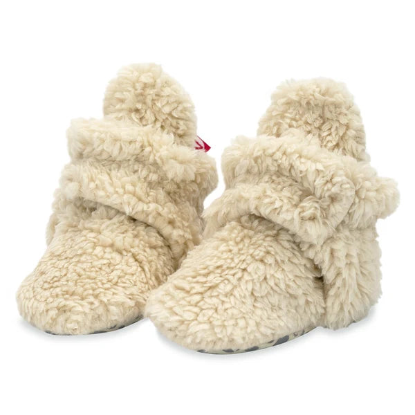 Pair of Zutano Oat faux-fur baby booties with wraparound ankle straps and snap closures, shown from the front.
