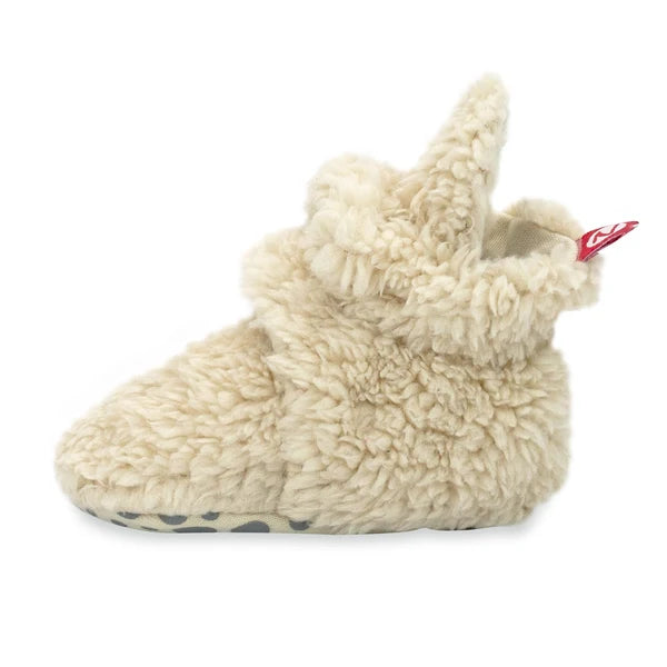 Side view of an Oat faux-fur baby bootie, showing its ankle strap and gripper sole along the bottom edge.
