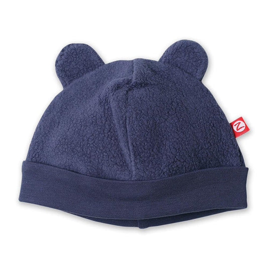 Zutano Denim Navy fleece baby hat with two rounded bear ears, a wide folded band and a small red brand tag.
