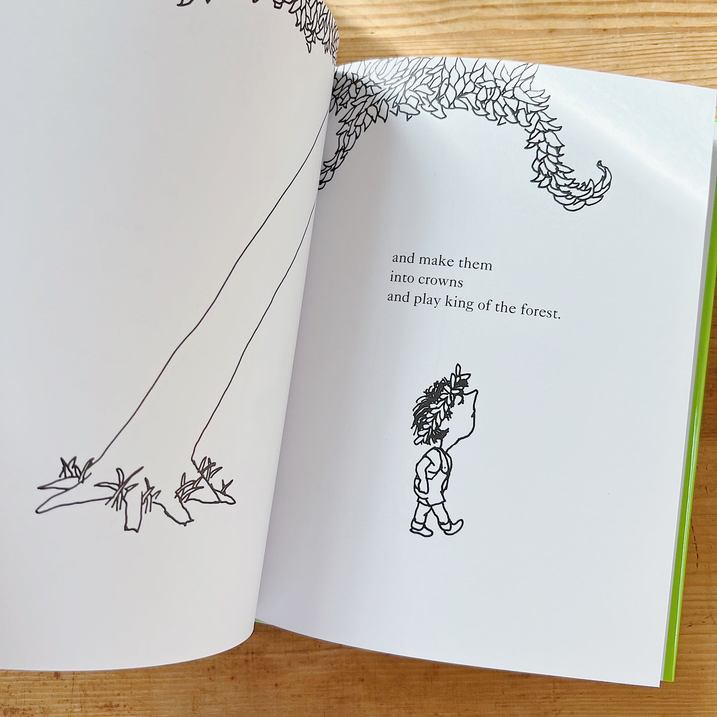 Open interior spread of The Giving Tree showing two pages: on the left, a black-and-white line illustration of the tree's bare trunk and roots; on the right, a black-and-white illustration of the boy wearing a leafy crown on his head and walking away holding a large leafy branch as a flag, with the text "and make them into crowns and play king of the forest," displayed on a warm wood surface.
