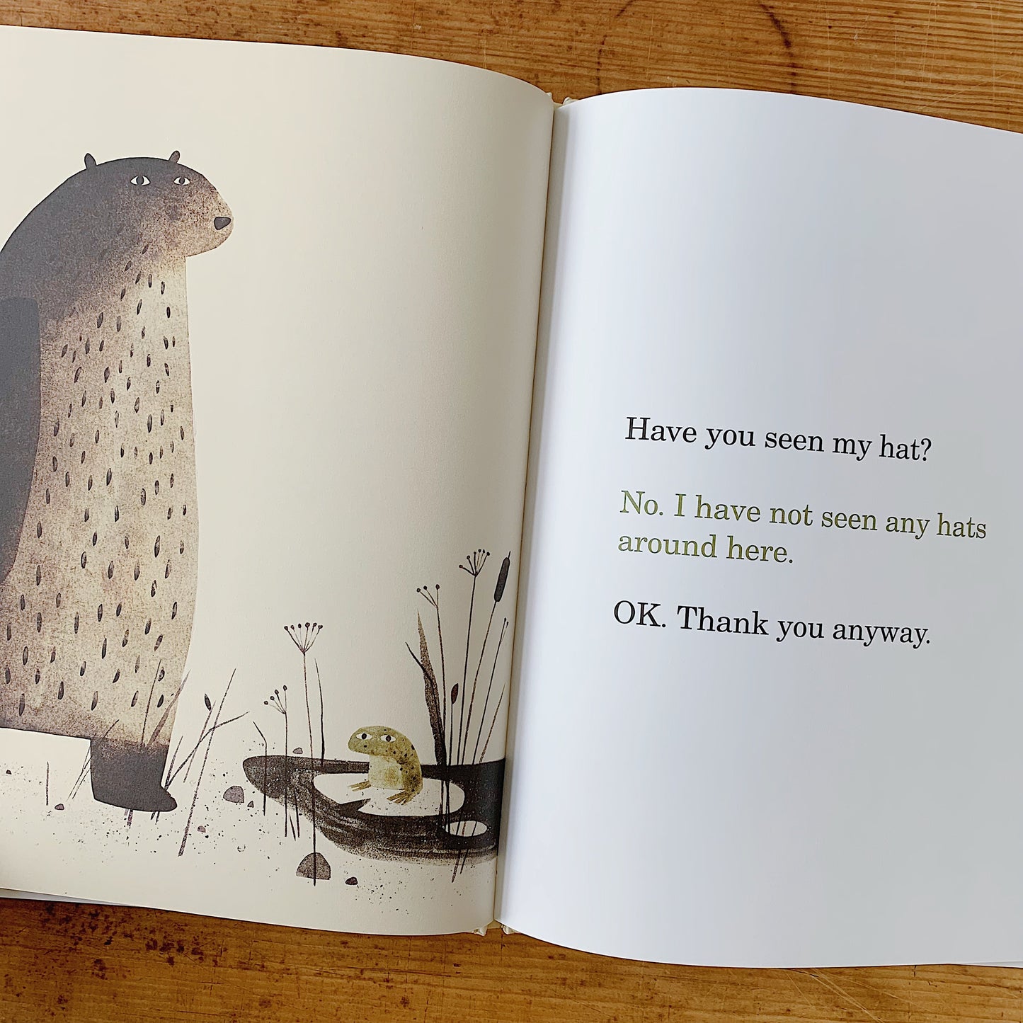Interior spread of I Want My Hat Back showing the bear towering over a small green frog in a marsh, beside dialogue text reading "Have you seen my hat? No. I have not seen any hats around here. OK. Thank you anyway."
