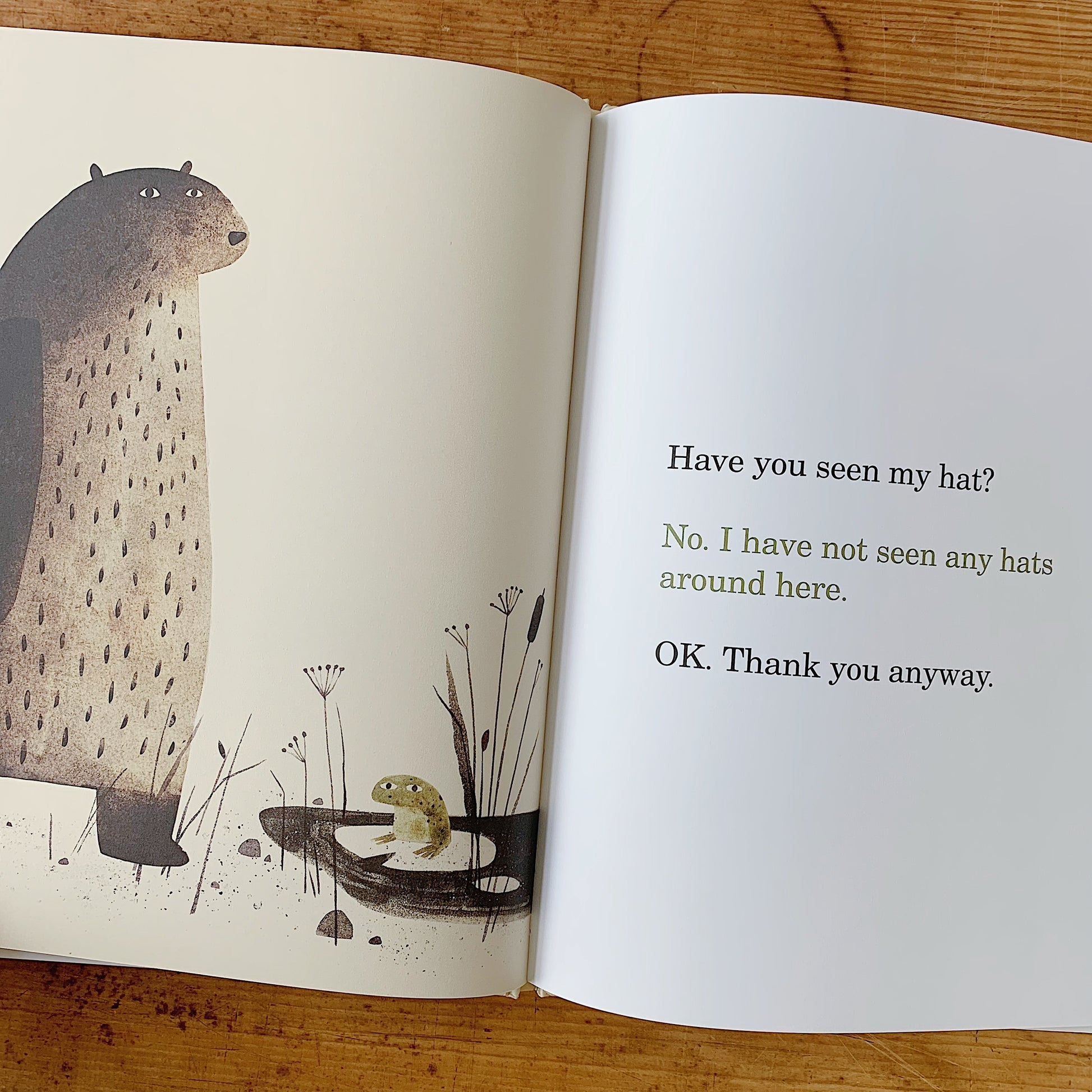 Interior spread of I Want My Hat Back showing the bear towering over a small green frog in a marsh, beside dialogue text reading "Have you seen my hat? No. I have not seen any hats around here. OK. Thank you anyway."
