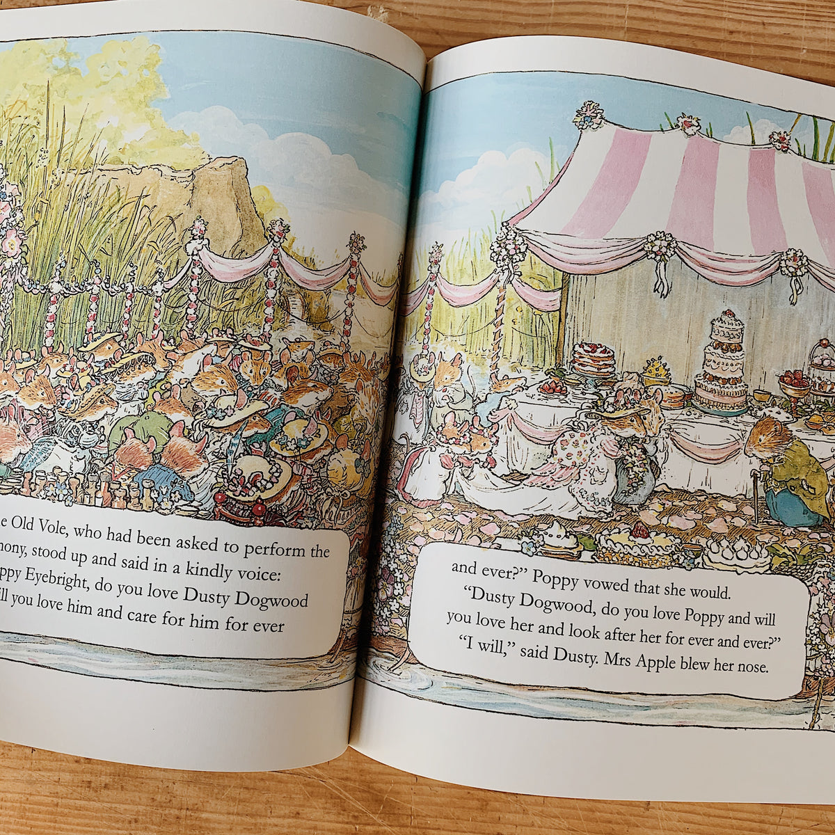 Open pages of The Complete Brambly Hedge showing a mouse wedding beneath a pink-and-white canopy, with guests and a tiered cake.
