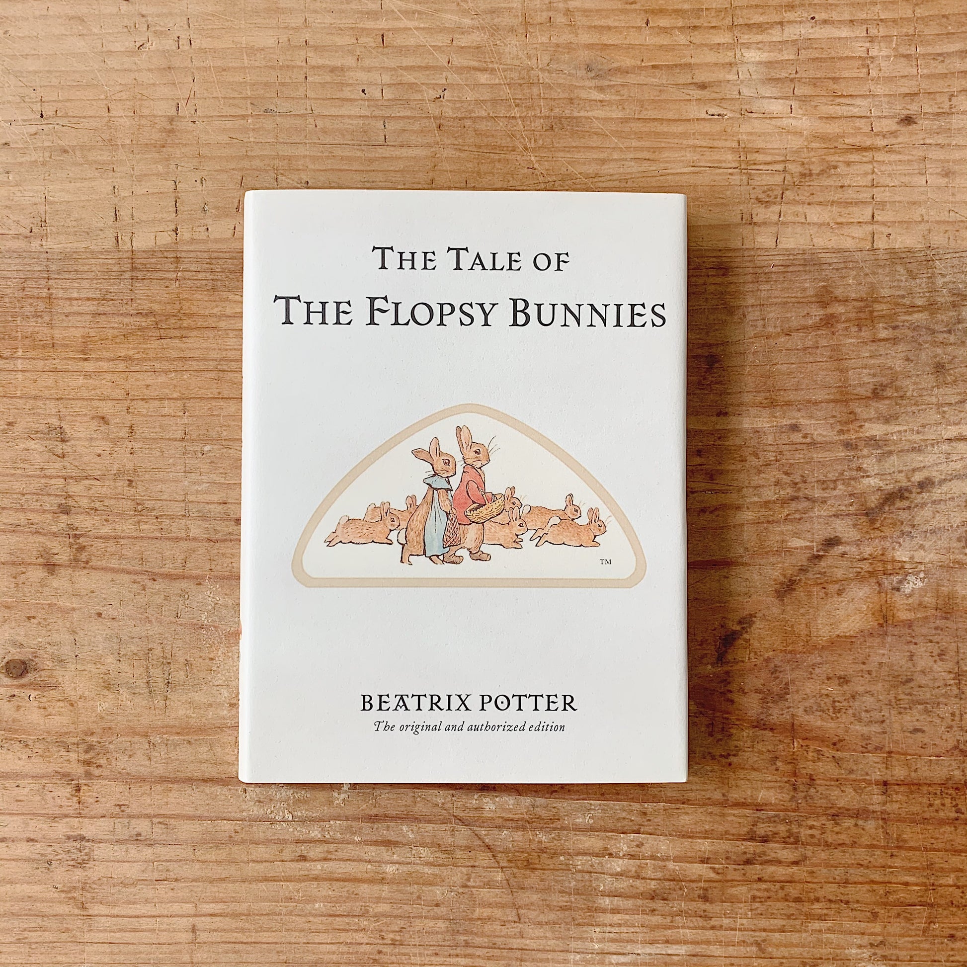 The book 'The tale of flopsy bunnies laydown' cover shot top view on wooden background